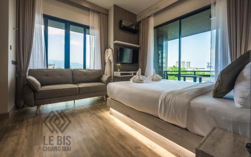 1 dormitorio con cama, sofá y ventanas en Le Bis Hotel en Chiang Mai