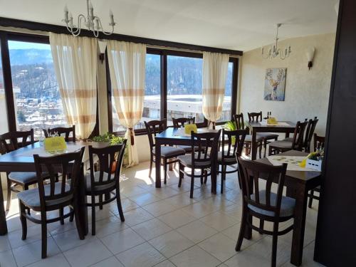 een eetkamer met tafels, stoelen en ramen bij Family Hotel Bela in Tryavna