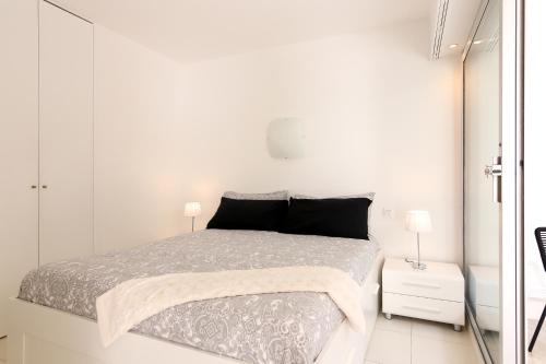a white bedroom with a bed and two lamps at Rocamare in Menton