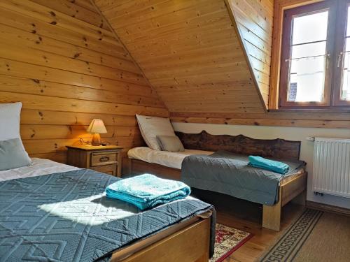sypialnia z 2 łóżkami w drewnianym domku w obiekcie Dolina Biebrzy - Ośrodek Agroturystyczny w mieście Wroceń