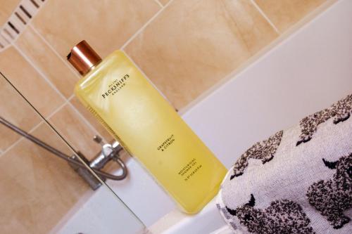 a yellow bottle sitting on the side of a bath tub at Whispering Place Georgian Grade II Sleeps 6 Adults 3 mins from Safari Park & Steam Train in Bewdley