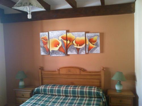 four paintings on a wall above a bed at Casa Rural Valle Tosande in Cantoral