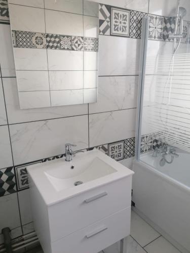 une salle de bain avec un lavabo, un miroir et une baignoire dans l'établissement Eden Host, à Clermont-Ferrand