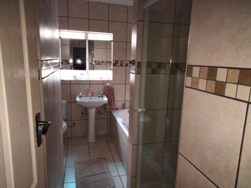 a bathroom with a shower and a sink and a tub at Turn and slip in Bloemfontein