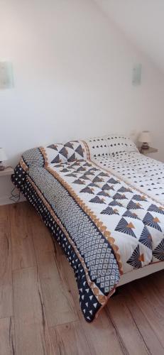 a bed with a quilt on top of a wooden floor at La plage in Audierne
