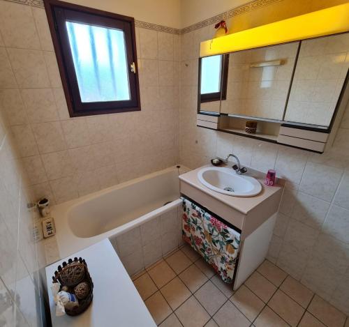 La salle de bains est pourvue d'un lavabo, d'une baignoire et d'un miroir. dans l'établissement Maison 100m2, espaces verts, 8 min à pied du lac, piste cyclable, à Sévrier