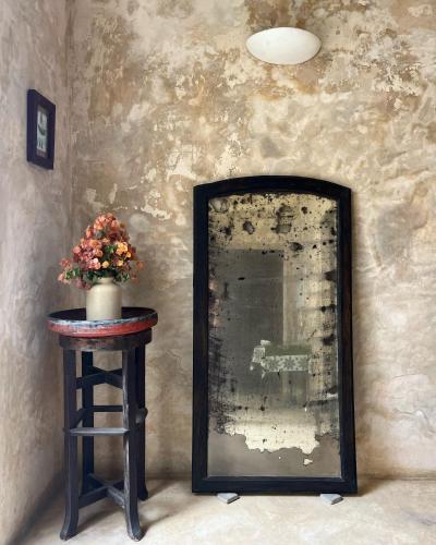a mirror sitting on a table next to a stool with flowers at Subira House in Lamu