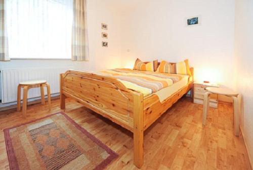 ein Holzbett in einem Zimmer mit zwei Hockern in der Unterkunft Ferienwohnung Riegstra in Esens