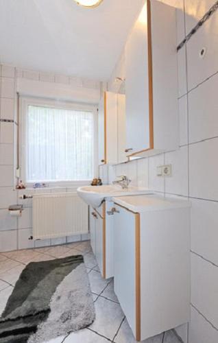 a white bathroom with a sink and a window at Ferienwohnung Riegstra in Esens