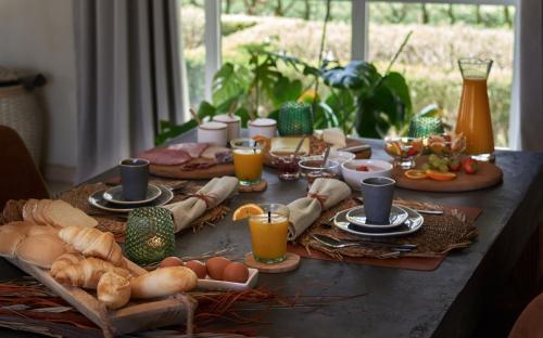 una mesa de desayuno con huevos, pan y vasos de zumo de naranja en B&B Pura Vista en Zandhoven