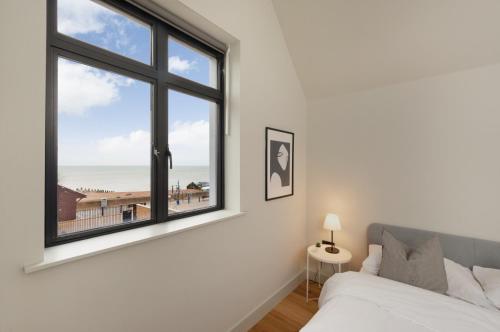 a bedroom with a bed and a window with a view of the beach at Home with sea views next to the beach! in Kent