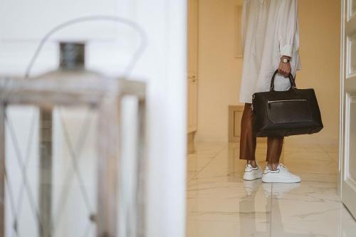 Una donna che tiene una borsa nera in un corridoio di EL GUSTO HOMES Town a Sopron