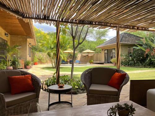 Usa River的住宿－Sunbird Cottage，庭院设有两把椅子和一张桌子,庭院