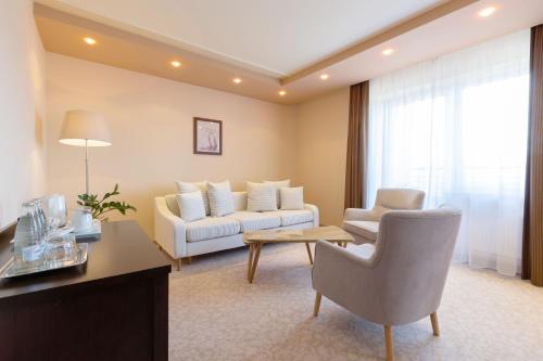 a living room with a couch and a table at Hotel Kudowa Manufaktura Relaksu in Kudowa-Zdrój