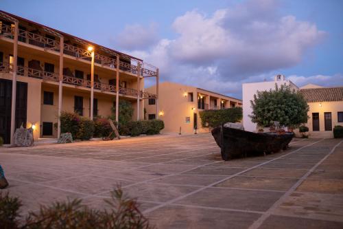 a courtyard of a building with a tree in the middle at La Tonnara di Bonagia Resort in Valderice