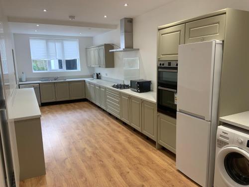 a kitchen with wooden floors and a white refrigerator at Entire Seaside Home, Sleeps 8, All en-suite rooms in New Brighton