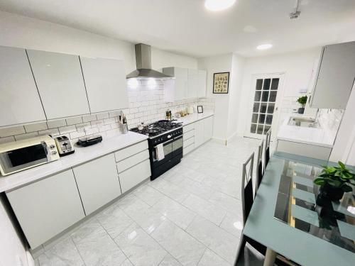 uma cozinha com armários brancos e uma mesa de jantar em Leytonstone House - SleepyLodge em Londres