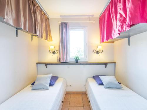 deux lits dans une chambre avec une fenêtre dans l'établissement Apartment Les Calanques Spa Thalassothérapie-2 by Interhome, aux Issambres