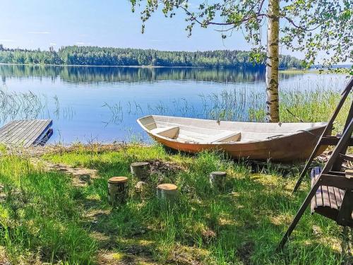 a boat sitting on the grass next to a lake at Holiday Home Pajuranta by Interhome in Oravi