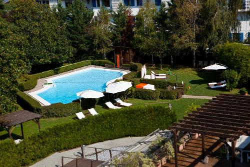 a swimming pool with chairs and umbrellas in a yard at Hotel Rio Bidasoa in Hondarribia