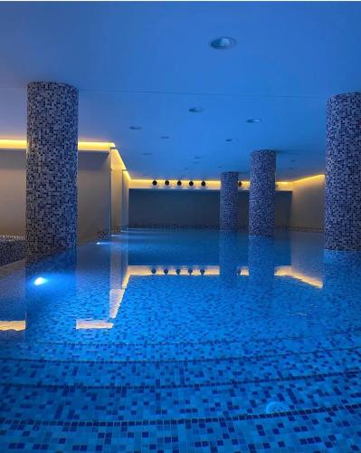 a swimming pool with blue lights in a building at NOVAK apartman in Vrnjačka Banja