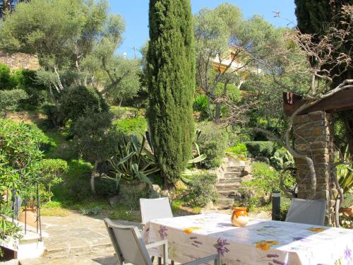 une table et des chaises dans un jardin arboré dans l'établissement Apartment Villa Montemare Colette by Interhome, au Lavandou