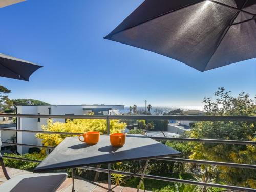 - une table avec 2 tasses et un parasol sur le balcon dans l'établissement Apartment Chenou-3 by Interhome, aux Issambres