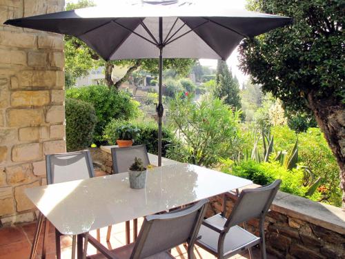 une table et des chaises blanches avec un parasol dans l'établissement Apartment Villa Montemare Babette by Interhome, au Lavandou
