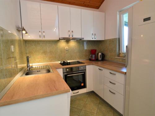 a kitchen with white cabinets and a sink at Holiday Home Camp Marko - ROZ335 by Interhome in Zečevo