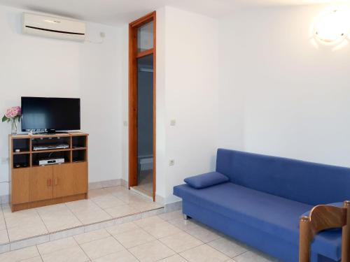 sala de estar con sofá azul y TV en Apartment Haus Peric - KOR201 by Interhome en Prigradica