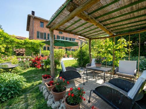 un patio con pergolato, sedie e fiori di Apartment Il Cortile by Interhome a Camerano Casasco