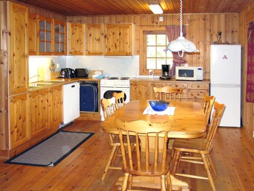 una cucina con tavolo in legno, sedie e frigorifero di Chalet Skogstjerna - FJS085 by Interhome a Viksdalen
