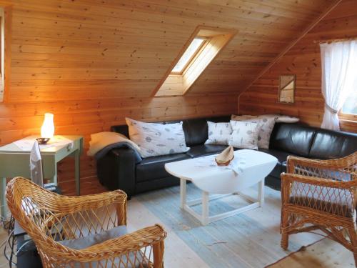 ein Wohnzimmer mit einem schwarzen Ledersofa und Stühlen in der Unterkunft Holiday Home Tufto by Interhome in Lunde