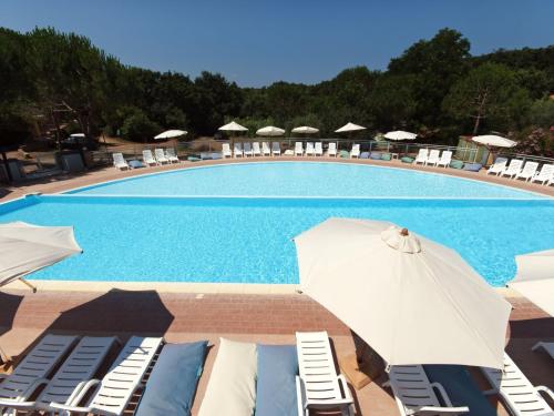 ein großer Pool mit Stühlen und einem Sonnenschirm in der Unterkunft Holiday Home Il Borgo-1 by Interhome in Casale Marittimo