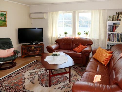un soggiorno con mobili in pelle e TV a schermo piatto di Holiday Home Kvamsvika - FJS560 by Interhome a Kvammen