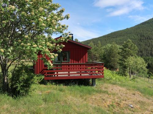 a red cabin in a field with a tree at Holiday Home Hammaren - FJS771 by Interhome in Kaupanger