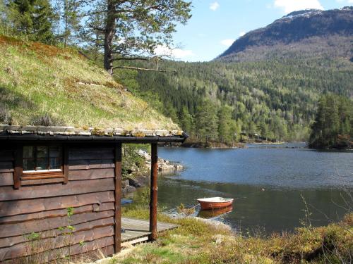 un pequeño edificio junto a un lago con un barco en Holiday Home Lauvavatnet - FJS087 by Interhome, en Viksdalen