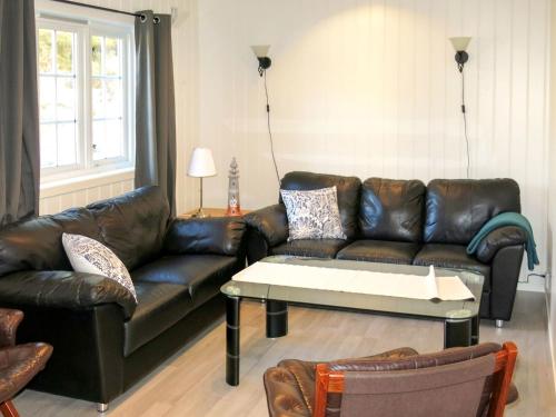 een woonkamer met een leren bank en een salontafel bij Holiday Home Nesjevik - FJS124 by Interhome in Leirvik