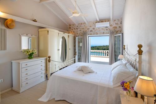 a white bedroom with a bed and a balcony at Waterfalls in Gaios