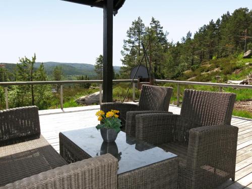 une terrasse avec des chaises en osier et une table fleurie. dans l'établissement Holiday Home Torebu - SOW108 by Interhome, à Øyuvstad