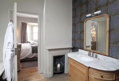 baño con chimenea, lavabo y espejo en No33 HUNSTANTON BOUTIQUE ROOMS en Hunstanton