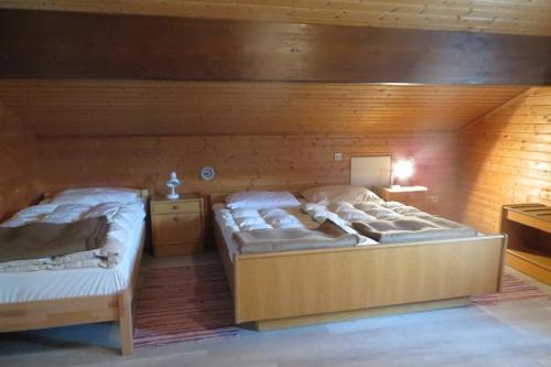 two beds in a room with wooden walls at Ferienhaus Petra in Regen