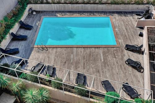 - une vue sur la piscine depuis la terrasse dotée de chaises dans l'établissement agreable 2 pieces avec piscine a1b235, à Cannes