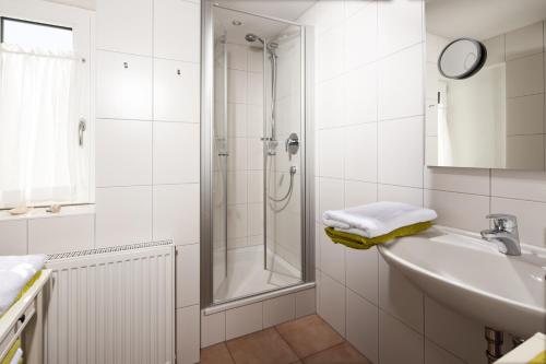 baño blanco con ducha y lavamanos en Villa Aldefeld en Berchtesgaden