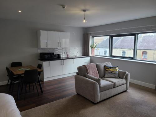 a living room with a couch and a table and a kitchen at Quay St Apartment in Sligo