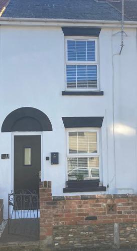 a white house with a black door and a window at Pier Road Holiday Home in Gorleston-on-Sea
