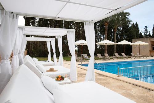 un dosel blanco sobre una piscina con sillas y sombrillas blancas en Principal Son Amoixa, en Manacor
