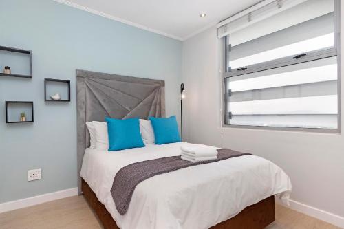 a bedroom with a large bed with blue pillows at Urban Oasis at Apex in Johannesburg