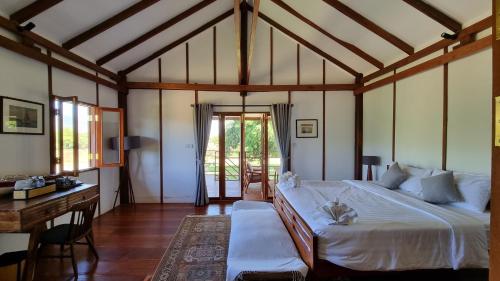 a bedroom with a large white bed and a desk at Khla Lodge in Kampot