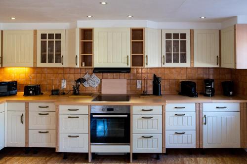 a kitchen with white cabinets and a stove top oven at Ferienhaus -Am alten Dorfplatz- in Dresden